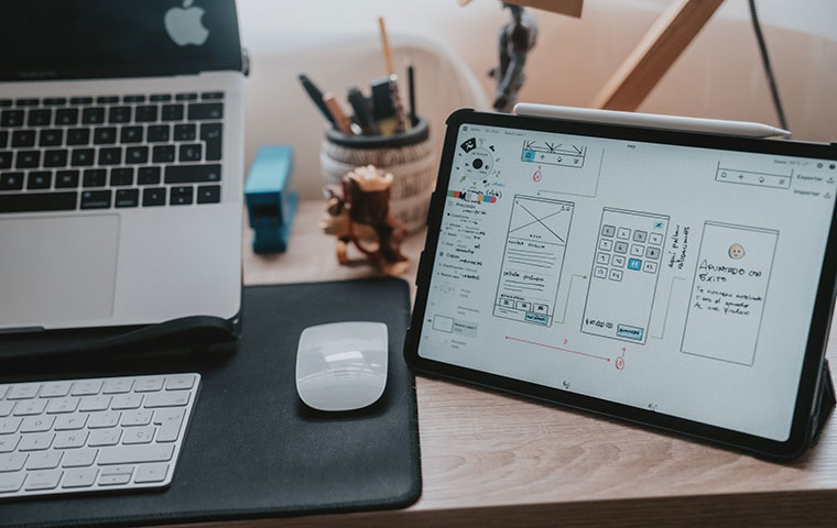 A photo of a mac book and iPad designing an app